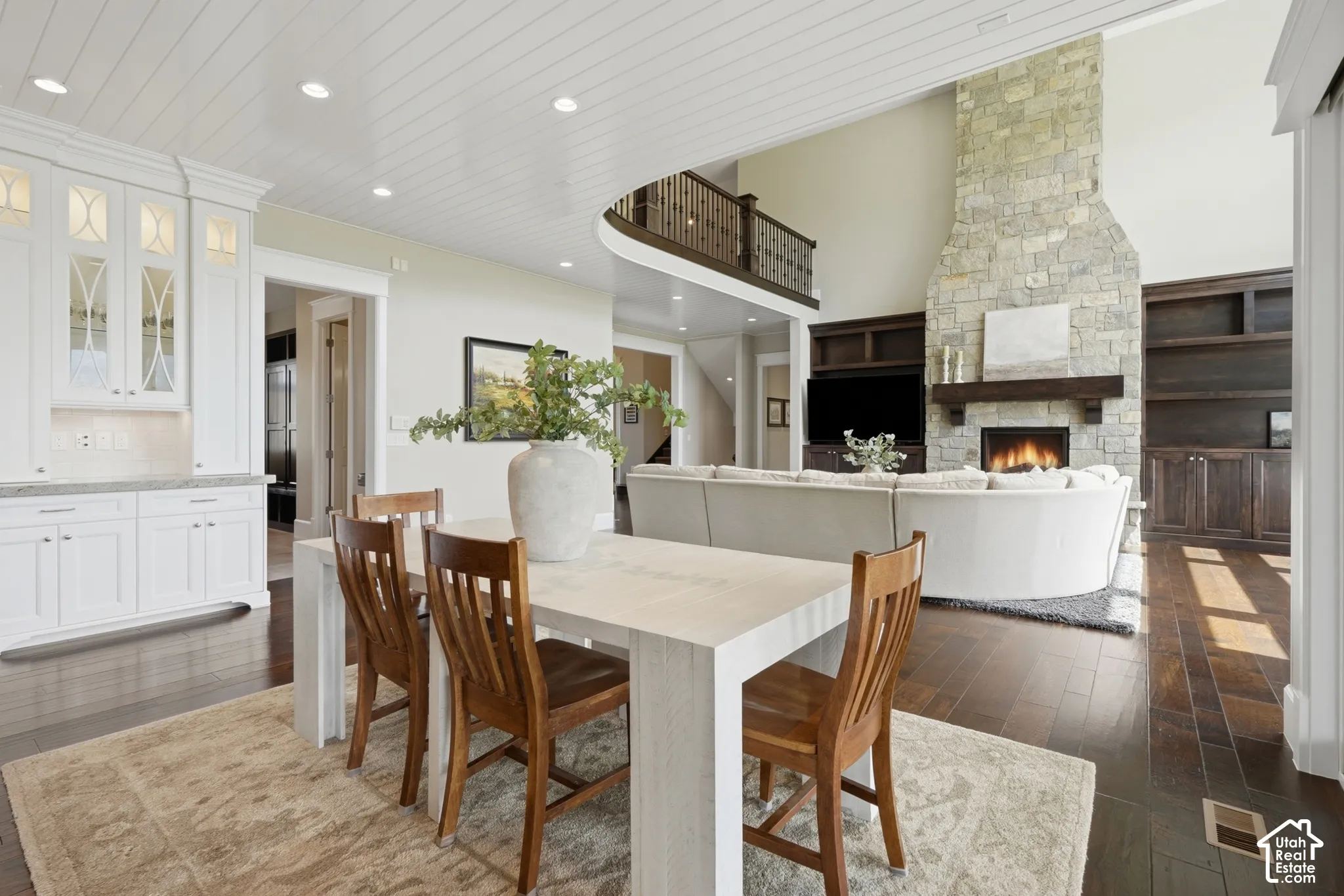 Spacious living area featuring a floor-to-ceiling stone fireplace, high ceilings, and dark wood-finish flooring