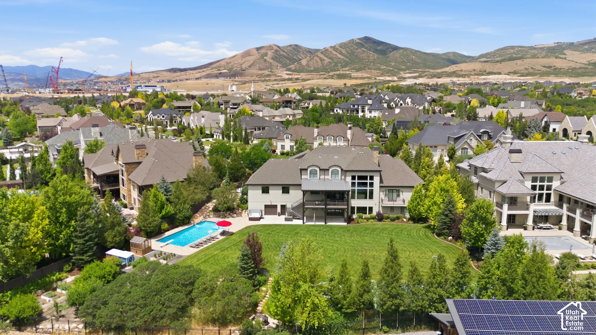 Expansive rear exterior featuring a multi-level deck, a large in-ground swimming pool, and a verdant lawn with mature trees