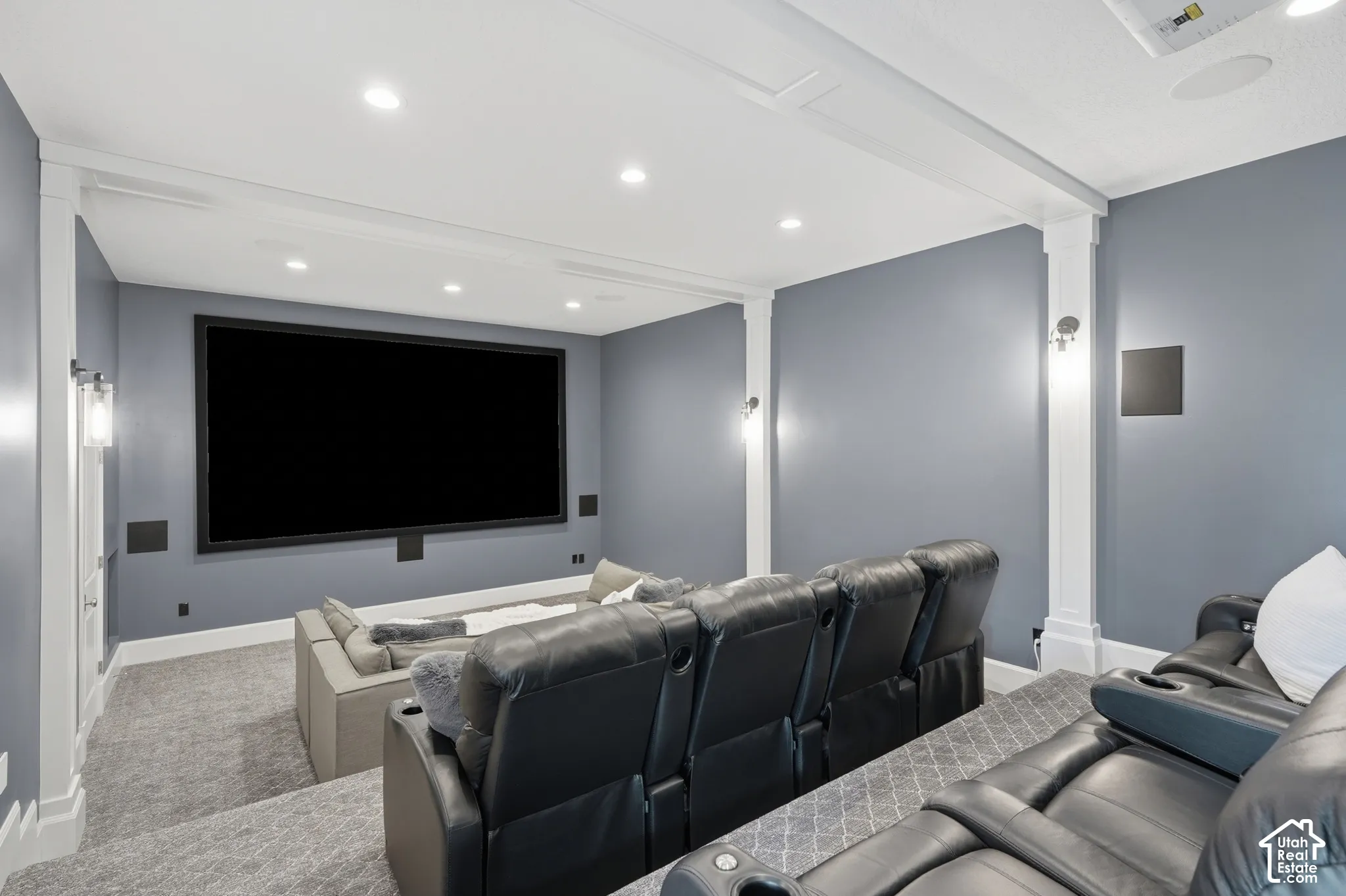 Dedicated media room featuring a large projection screen, recessed ceiling lighting, and wall sconces