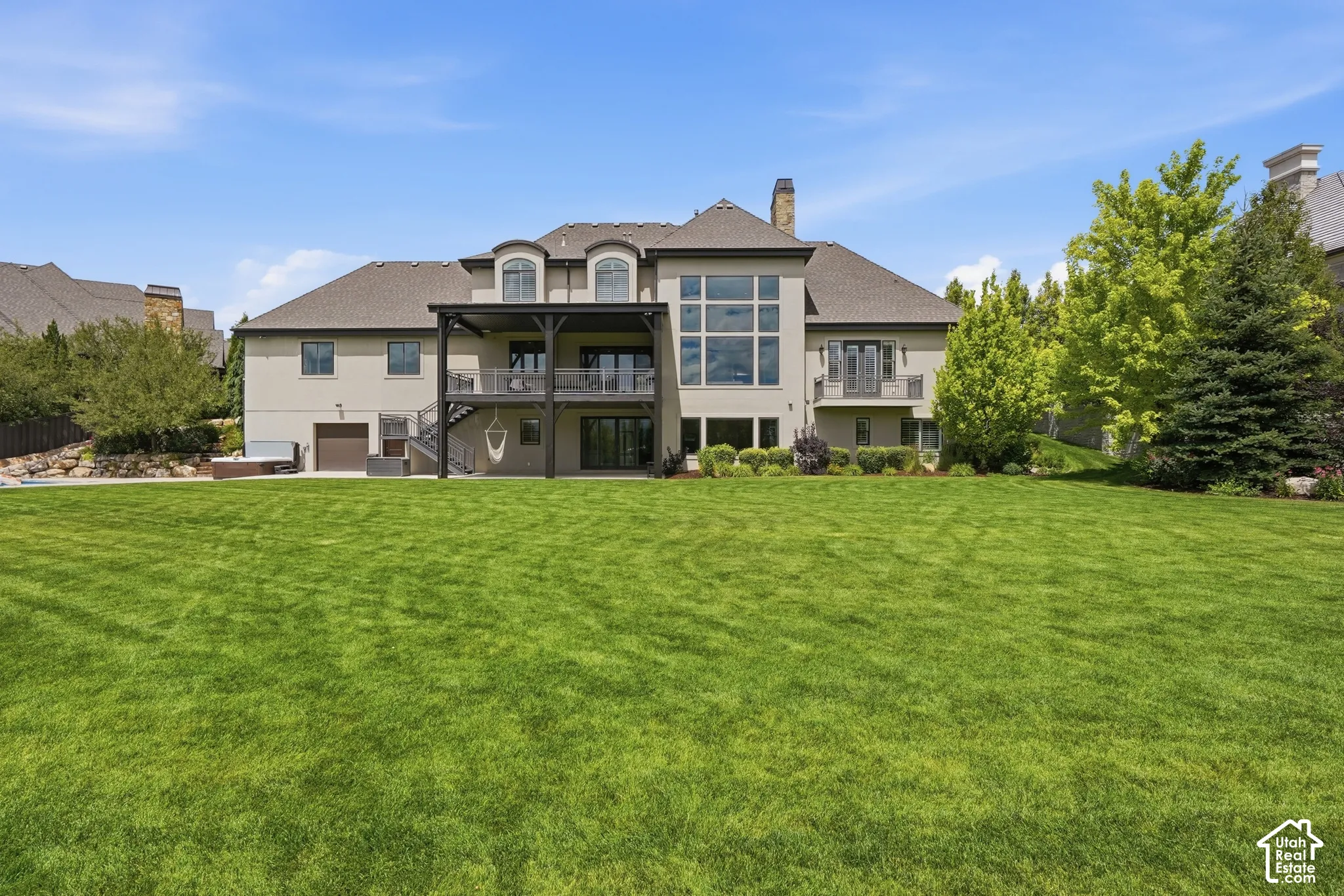 Expansive backyard with a manicured lawn, multi-level deck, and a lower-level patio