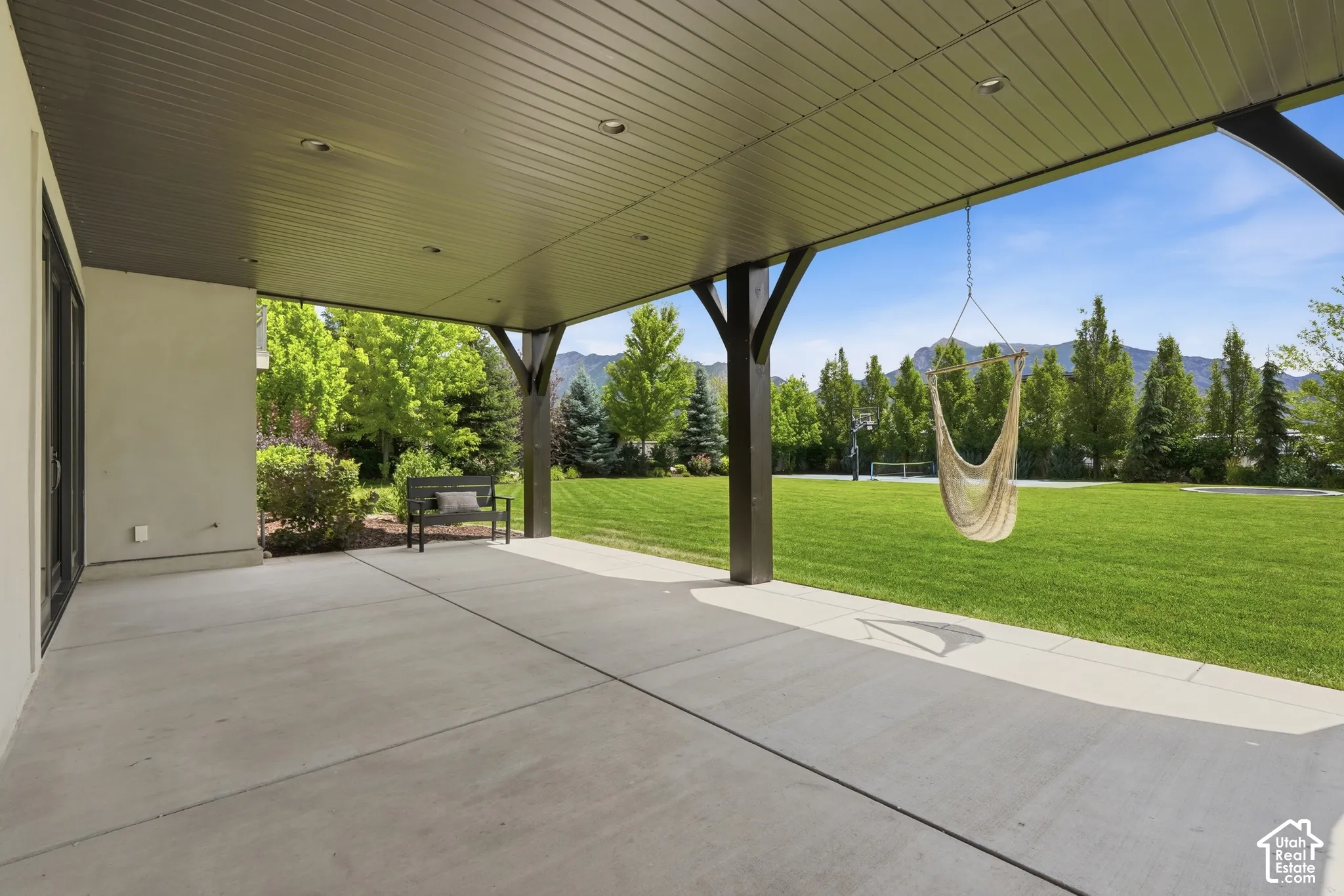 Expansive covered patio with recessed lighting, concrete flooring, and substantial structural posts