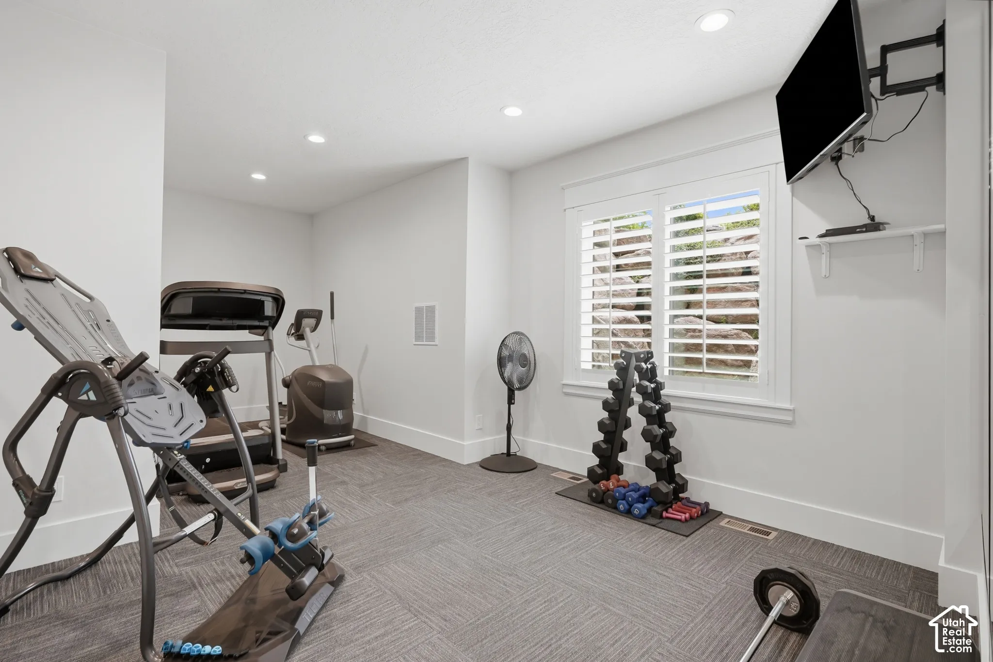 Recessed lighting illuminates this versatile room with patterned carpet flooring