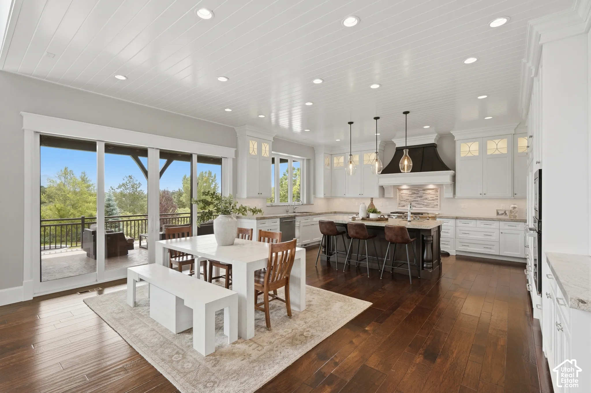 Open-concept kitchen and dining area featuring rich wood-finish flooring, a coffered ceiling with recessed lighting, and a large central island