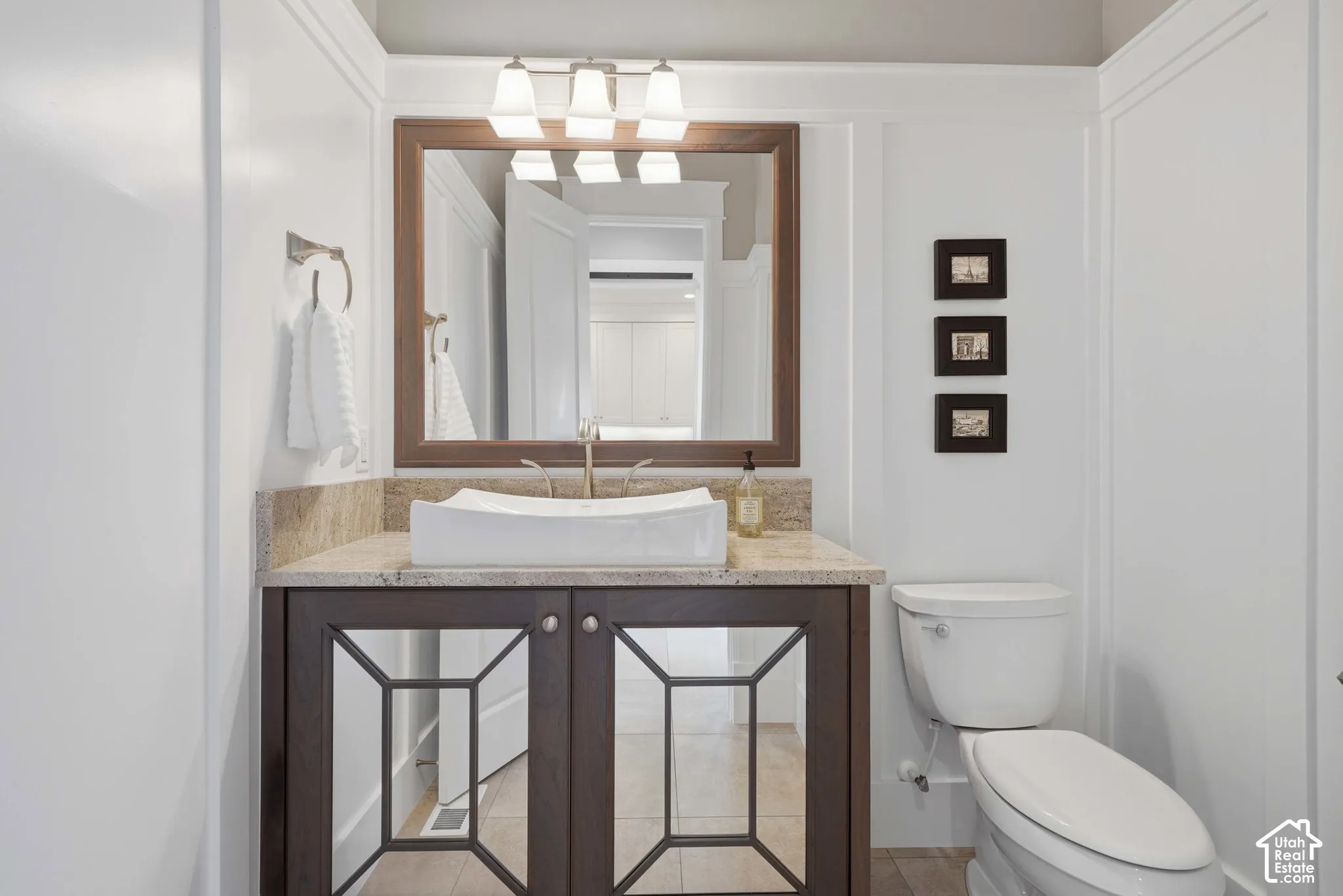 Vanity with a rectangular vessel sink, stone countertop, wood-frame mirror, and a three-light fixture