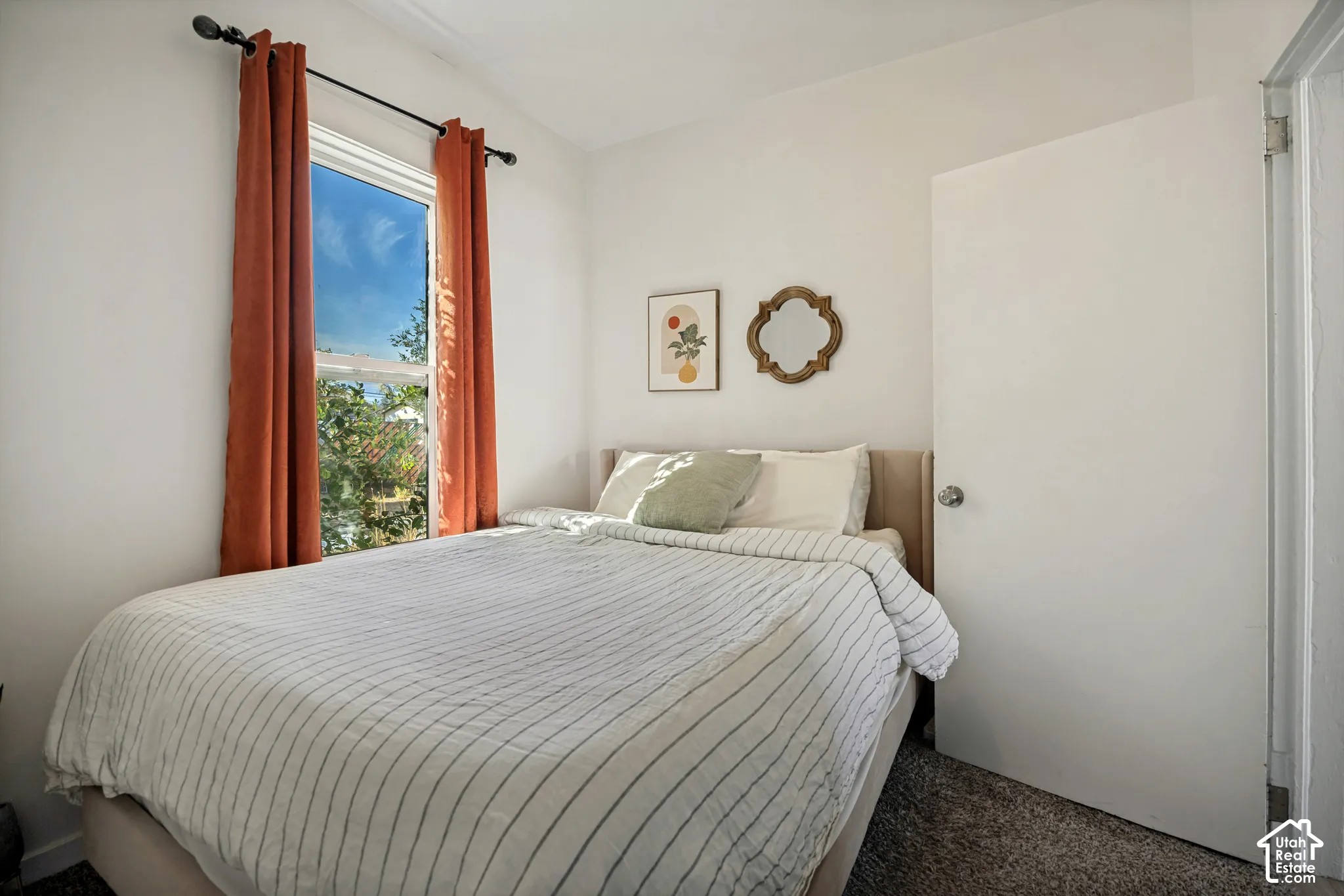 White walls with a single window, a solid door with a round knob, and neutral-toned carpeting