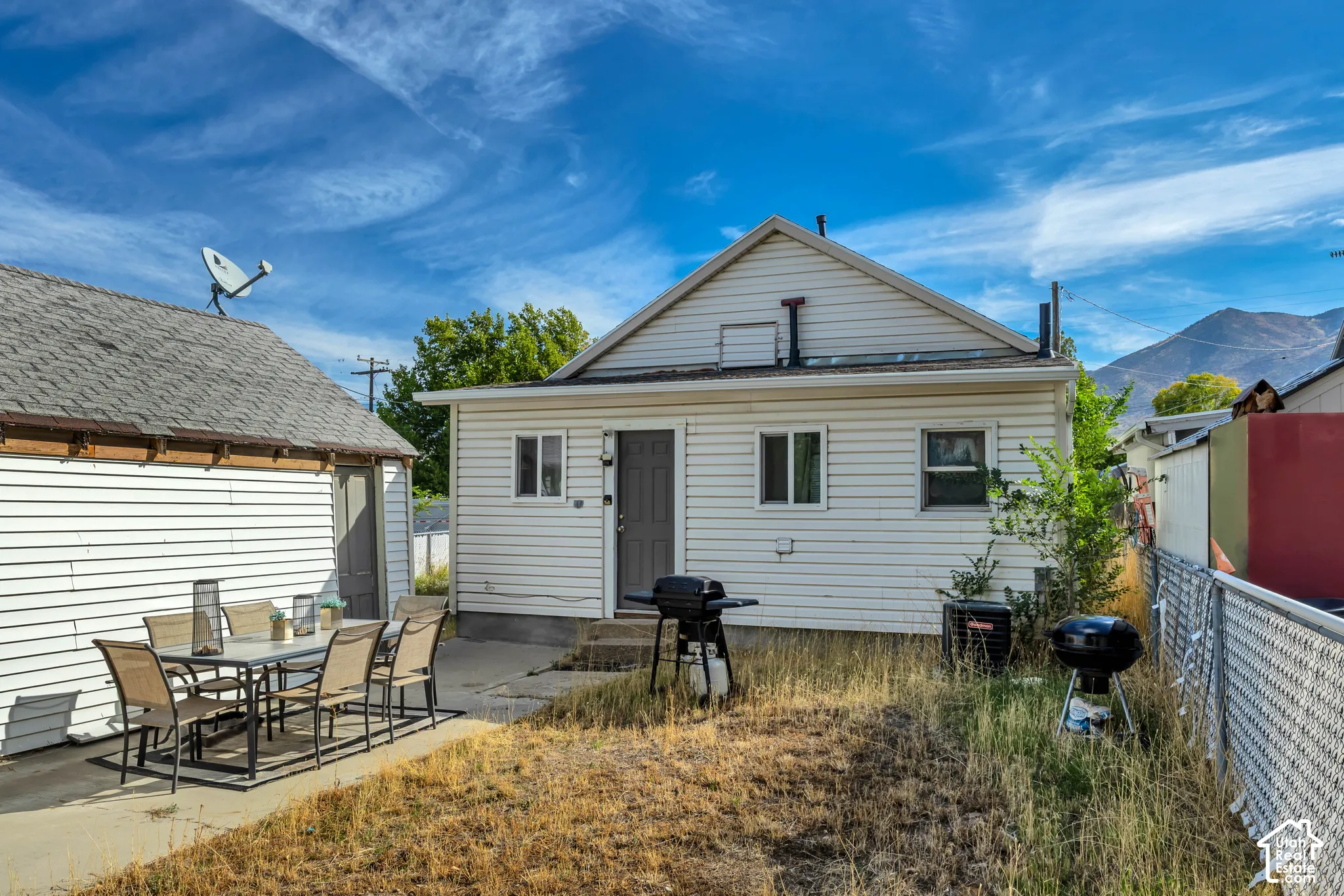 Rear exterior with white siding and a covered entry, featuring a concrete patio