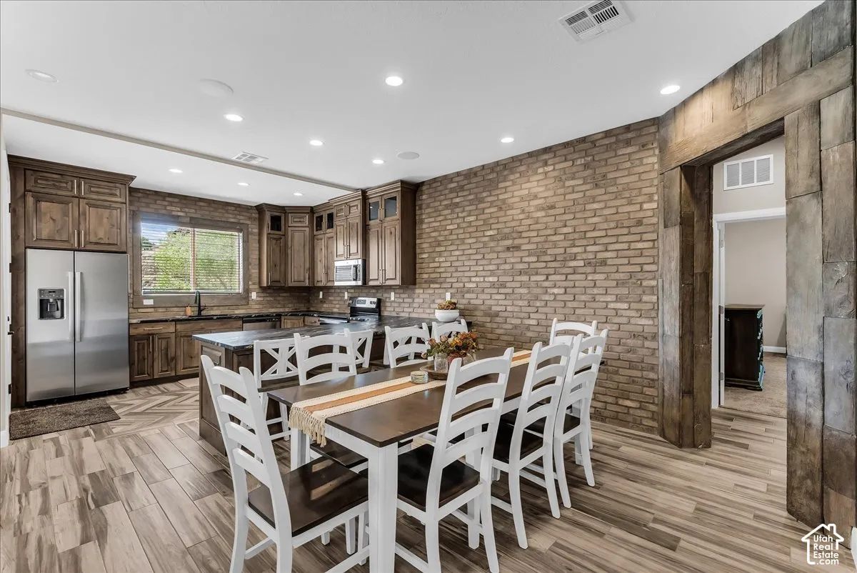 Gourmet kitchen with wood-finish flooring, recessed lighting, and brick accent wall