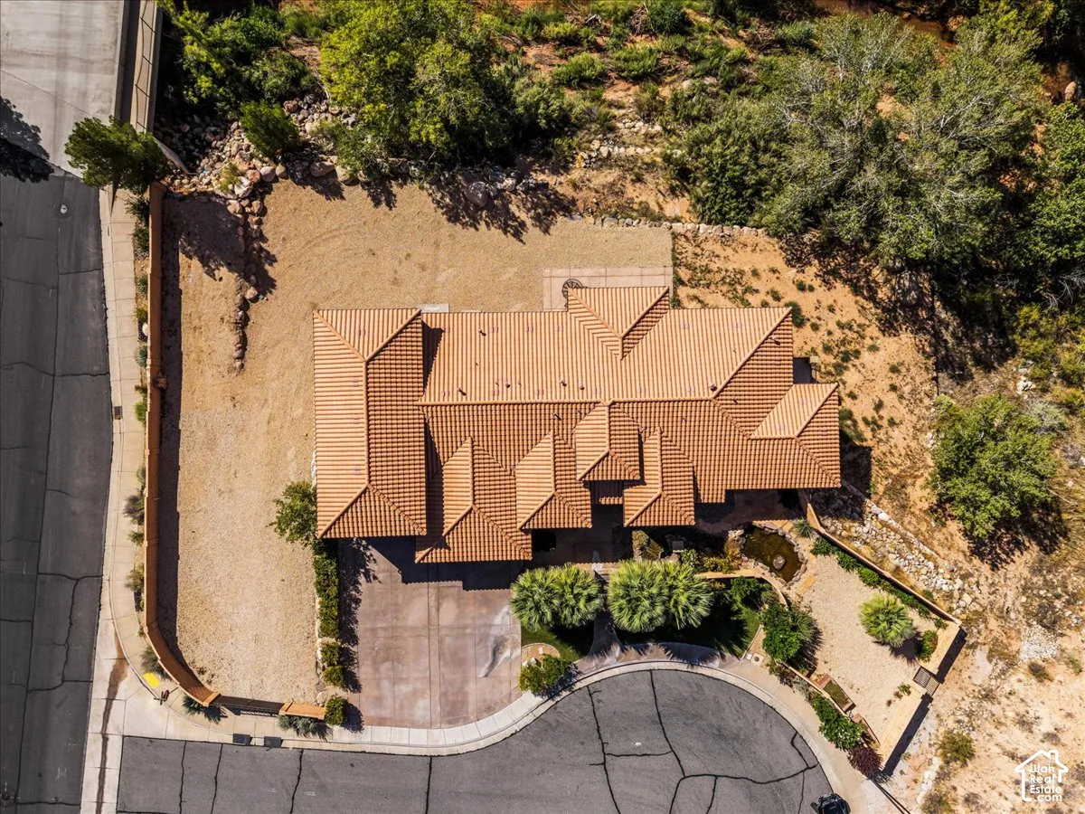 Terracotta tile roof, circular driveway, desert landscaping, stone retaining walls, and a visible water feature