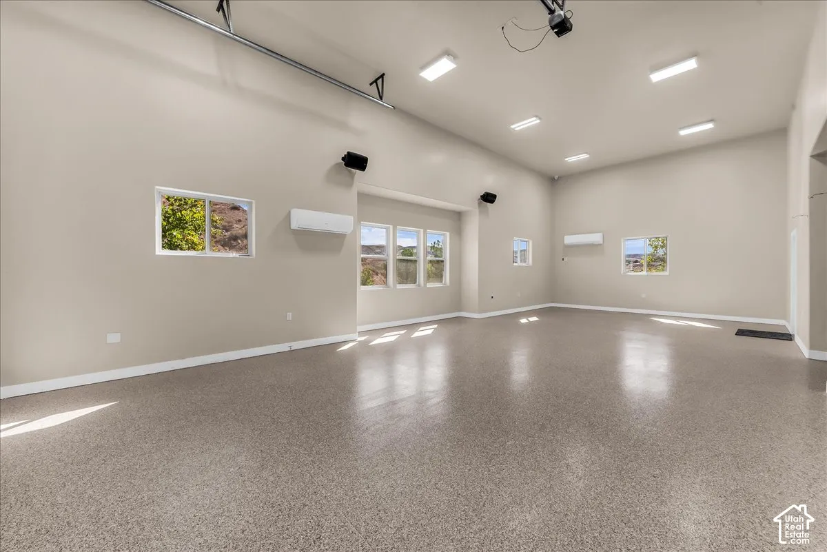 Spacious room featuring high ceilings, multiple windows, recessed lighting, and a durable speckled floor finish