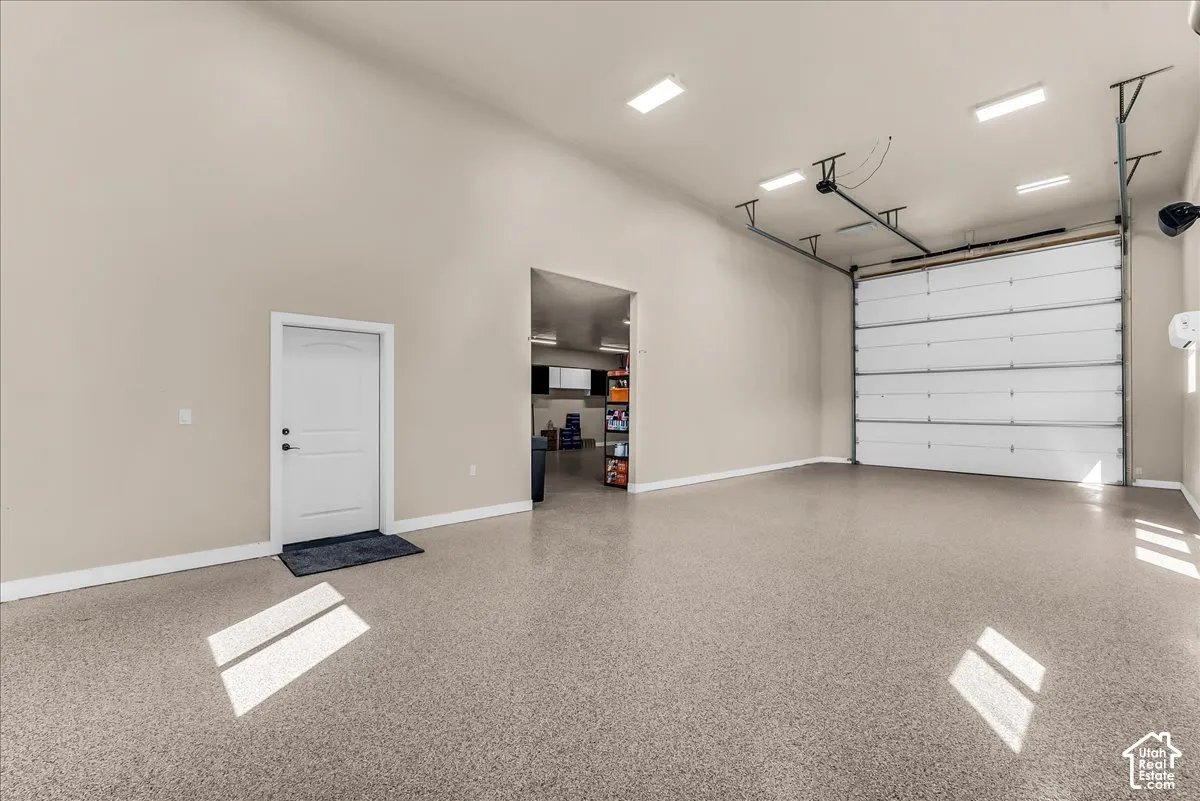 Spacious garage featuring a durable epoxy floor, vaulted ceiling, overhead lighting, and a large sectional garage door