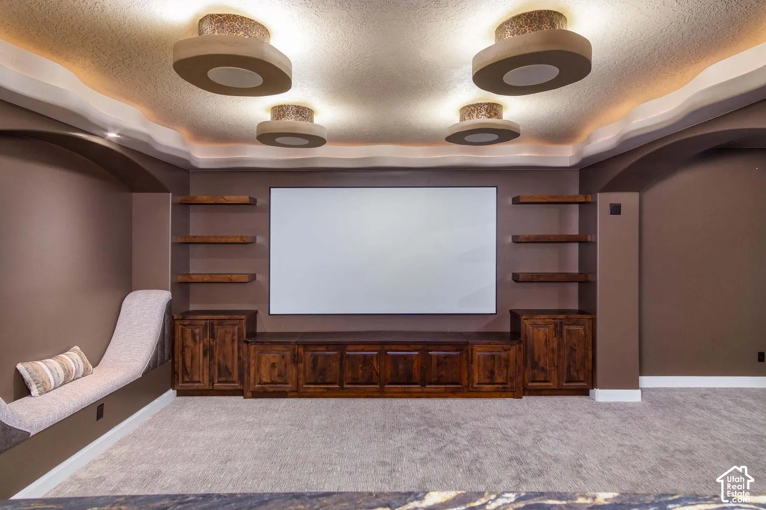 Built-in entertainment center with wood-finish cabinetry, floating shelves, and a large projection screen