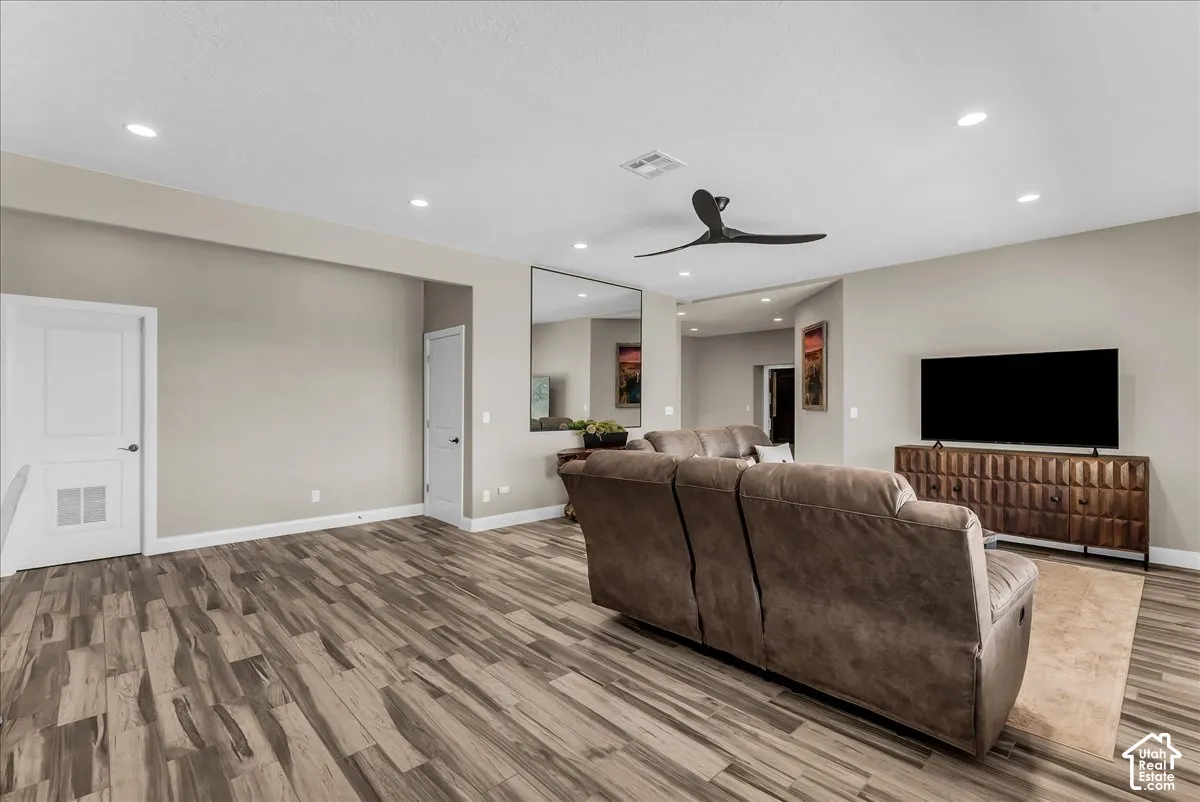 Spacious living area featuring wood-finish flooring, recessed lighting, and a modern ceiling fan