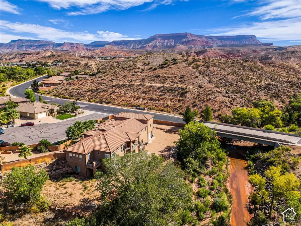 Terracotta tile roof, multi-level structure, paved driveway, surrounding mountainous landscape, and established trees