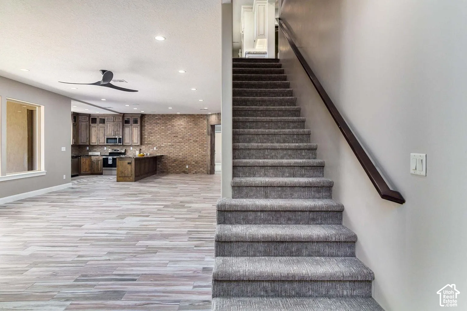 Open-concept living space with wood-finish flooring, recessed lighting, and a modern ceiling fan