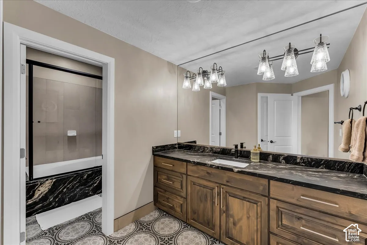 Double vanity with wood cabinetry and dark stone countertop
