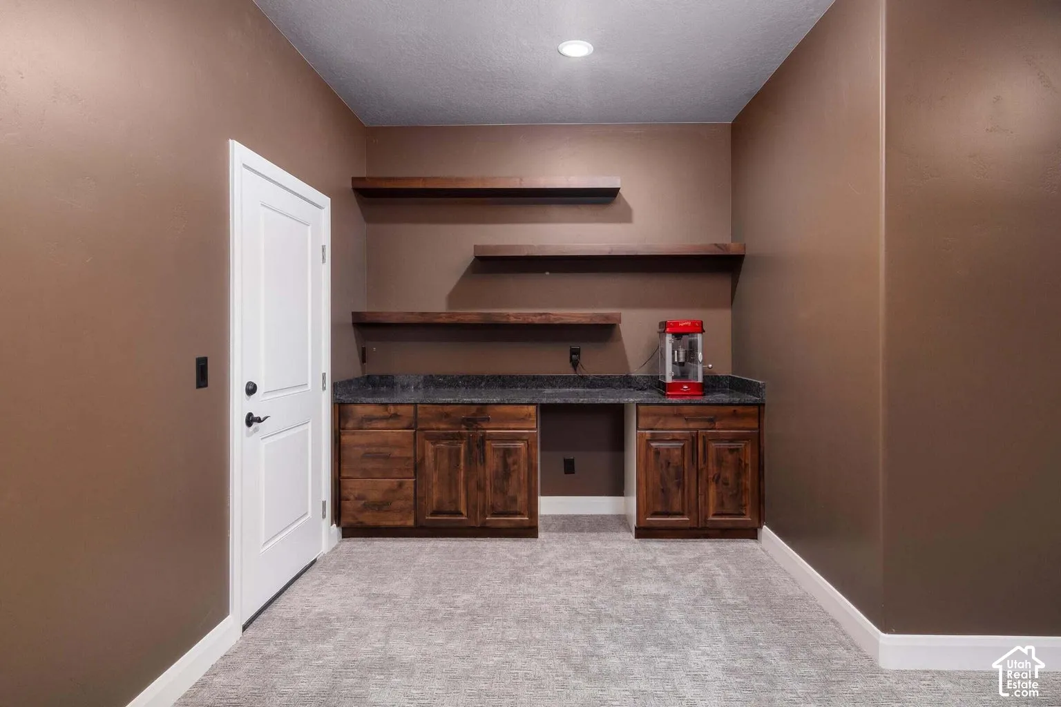 Built-in cabinetry with dark wood finish, dark stone countertop, and open shelving