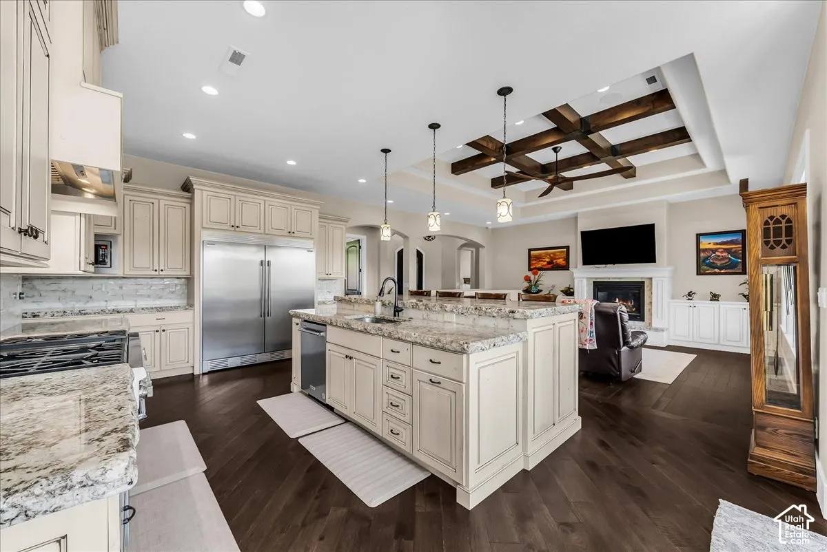 Gourmet kitchen with extensive light-toned cabinetry, stainless steel appliances, and a central island with a sink
