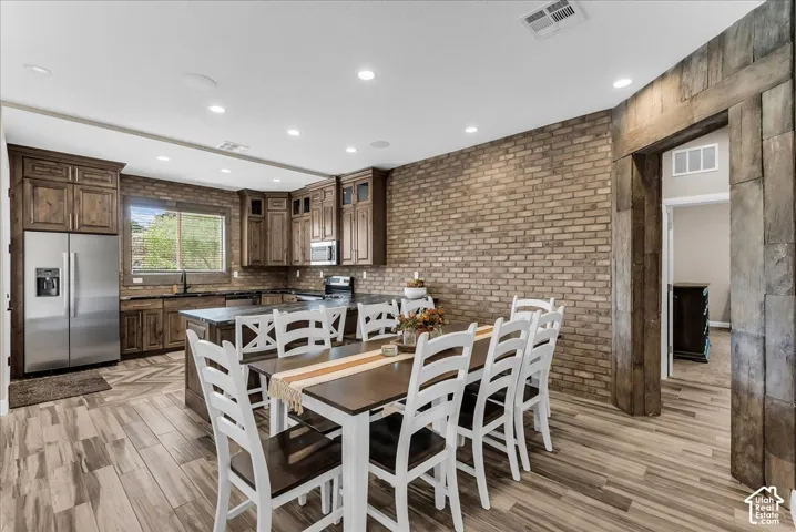 Gourmet kitchen with wood-finish flooring, recessed lighting, and brick accent wall