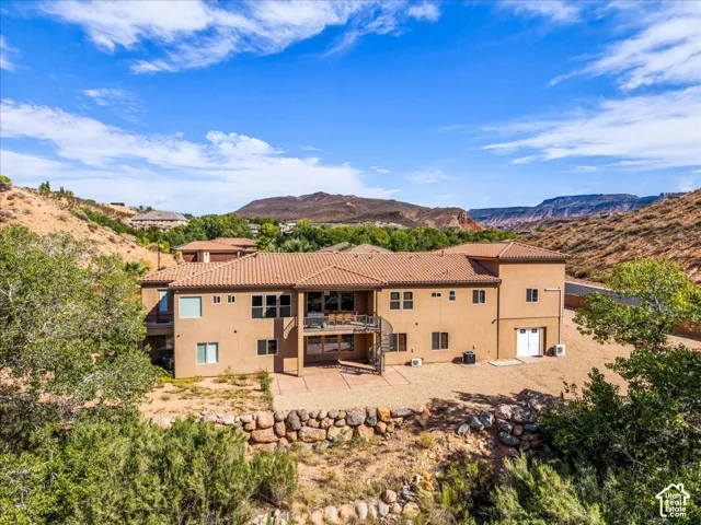 Terracotta tile roof, stucco exterior, multiple outdoor living spaces, and surrounding natural landscape
