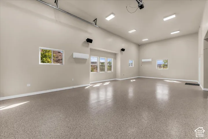Spacious room featuring high ceilings, multiple windows, recessed lighting, and a durable speckled floor finish
