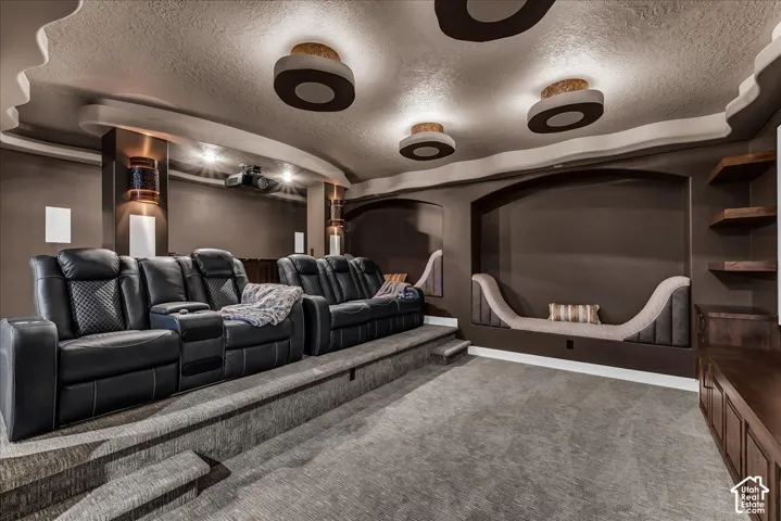 Built-in media room with tiered seating, architectural ceiling details, recessed lighting, and integrated wall sconces