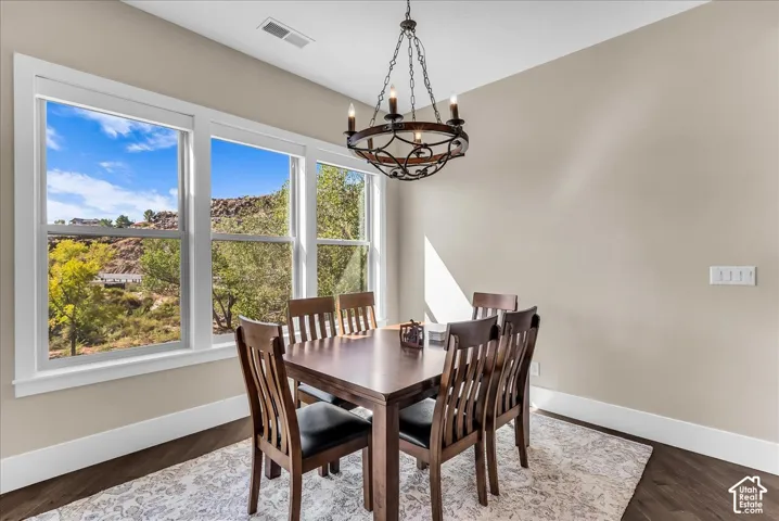 Wood-finish flooring, white window trim, and a decorative chandelier