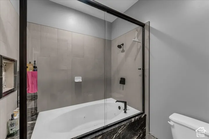 Built-in soaking tub with black accent fixtures and a black marble-style surround