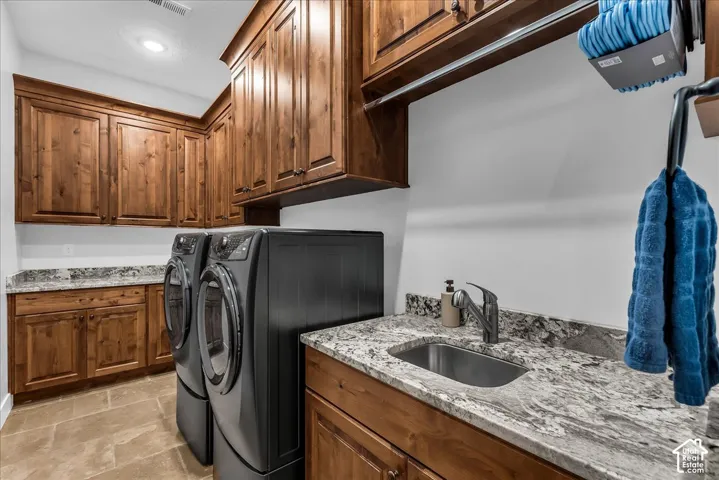 Warm wood cabinetry, stone-finish countertops, and a stainless steel utility sink