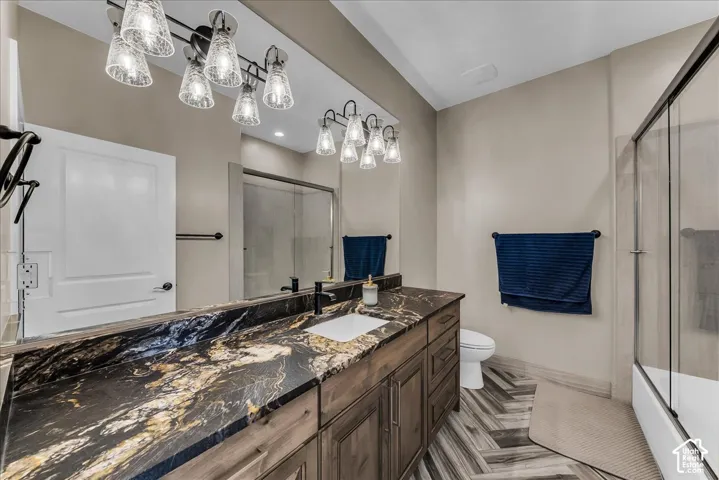 Long vanity with a dark wood finish and an integrated sink, dark patterned countertop, and a vanity-width mirror