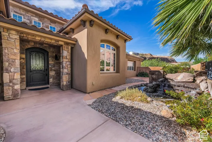 Stucco exterior featuring stone accents and a terracotta tile roof