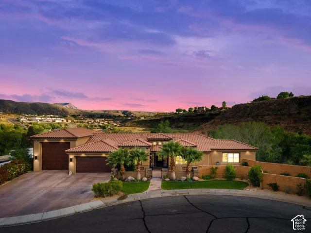 Terracotta tile roof, stucco exterior, multiple garage bays, desert landscaping, and a mountain backdrop