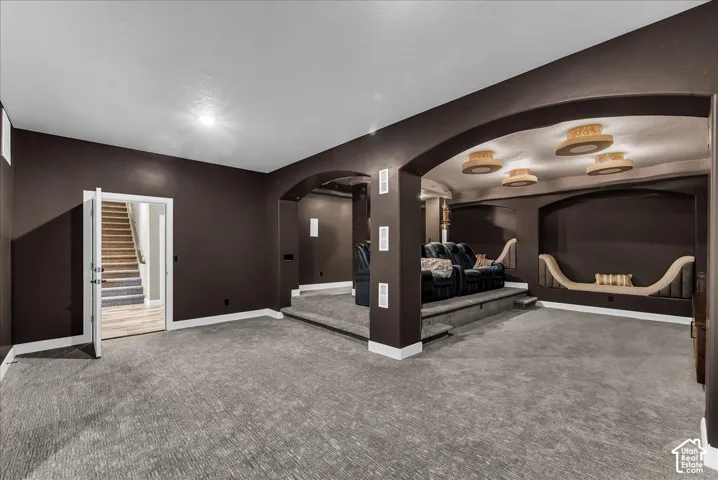 Spacious room featuring carpet flooring, archways, recessed lighting, and a raised platform