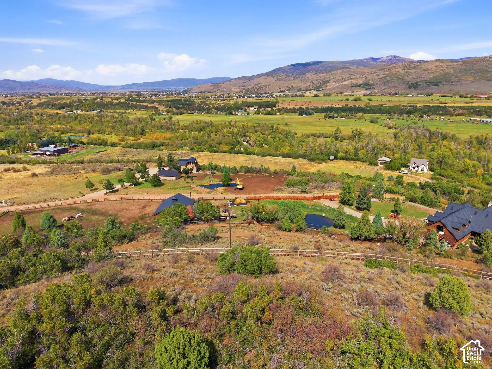 Expansive property featuring multiple structures, a pond, and surrounding natural landscaping
