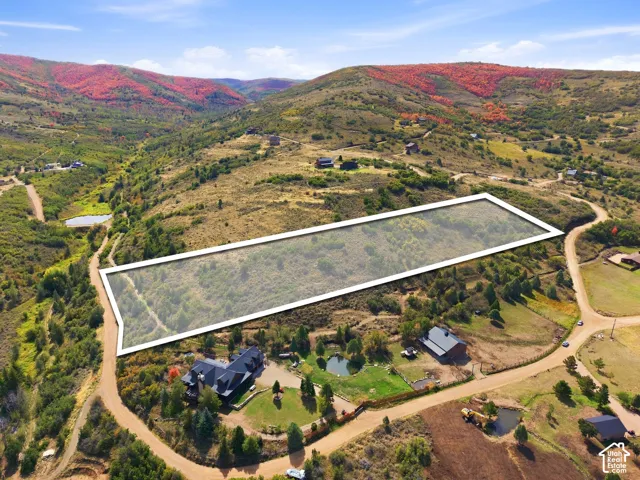 Expansive land parcel featuring natural topography, surrounding hillsides with varied foliage, and a clear boundary outline
