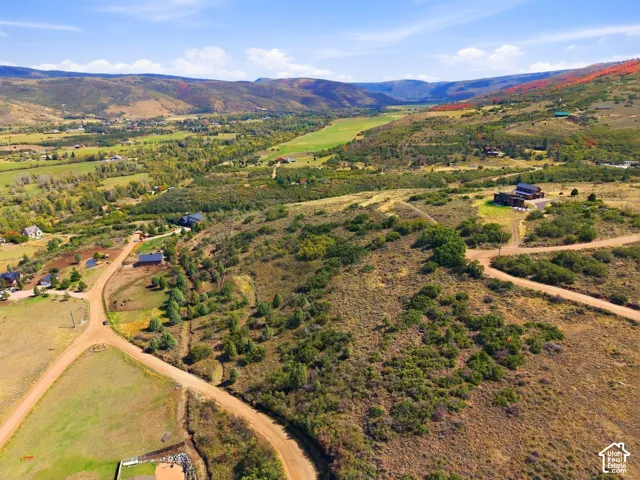 Expansive terrain featuring natural vegetation, distant hills, and multiple residential structures