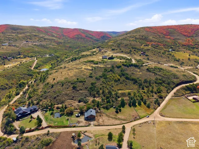 Expansive property featuring multiple structures, a pond, and surrounding hillsides with diverse foliage