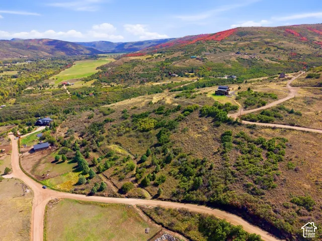 Expansive land parcel with surrounding hillsides, multiple established structures, and unpaved access roads
