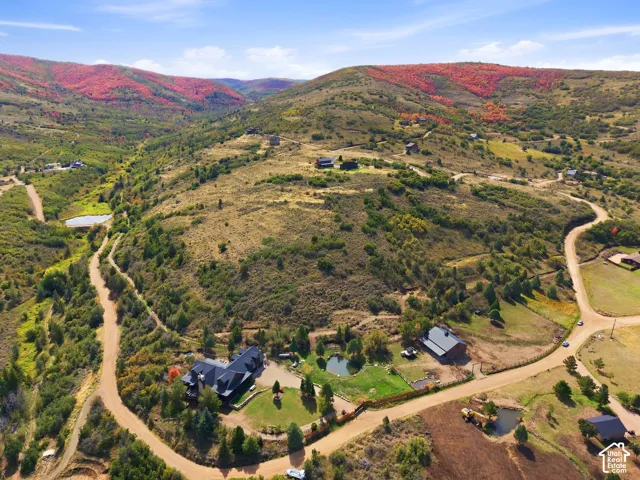 Expansive mountain property featuring a large residence, two distinct ponds, a detached barn, and a winding dirt road access