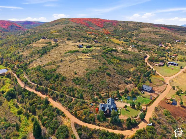Expansive mountain property featuring a main residence, additional structures, and multiple access roads