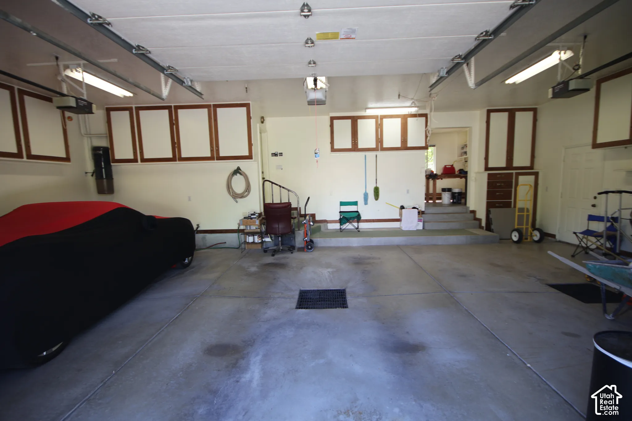 Spacious garage featuring a concrete floor, built-in cabinetry, overhead lighting, and an elevated entry