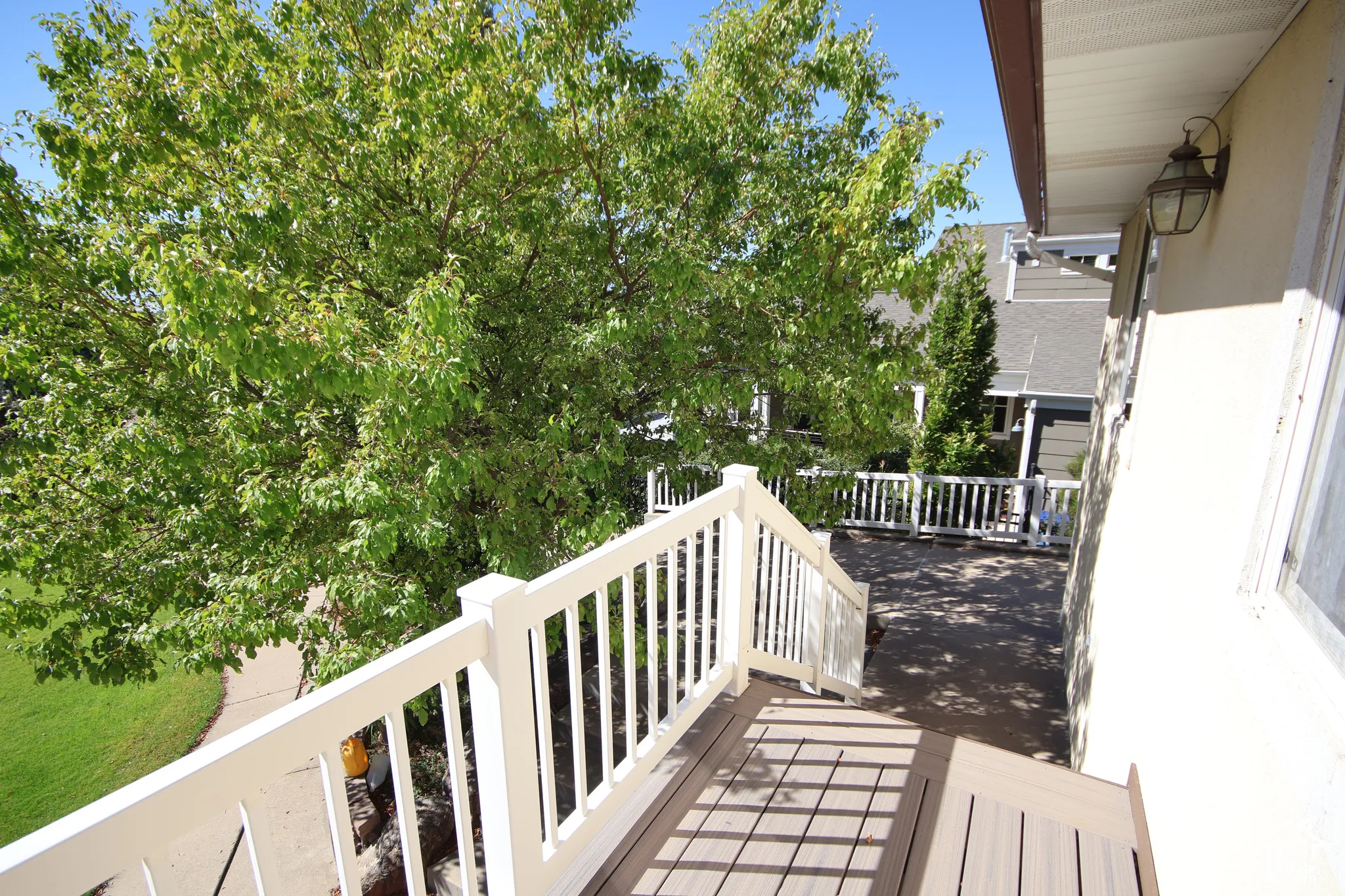 Outdoor deck with composite planking, white railing, and an exterior wall lantern