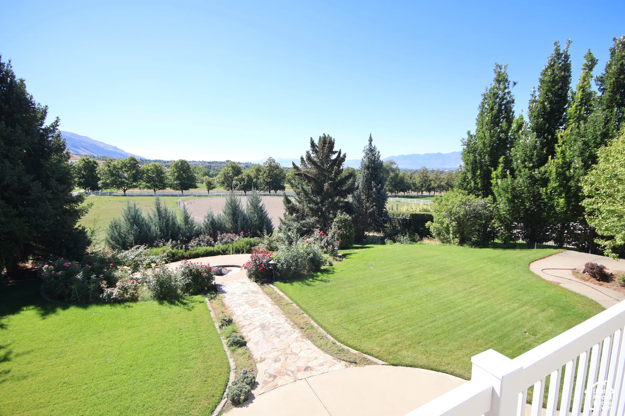 Expansive manicured lawn with mature trees, stone pathway, and perennial landscaping