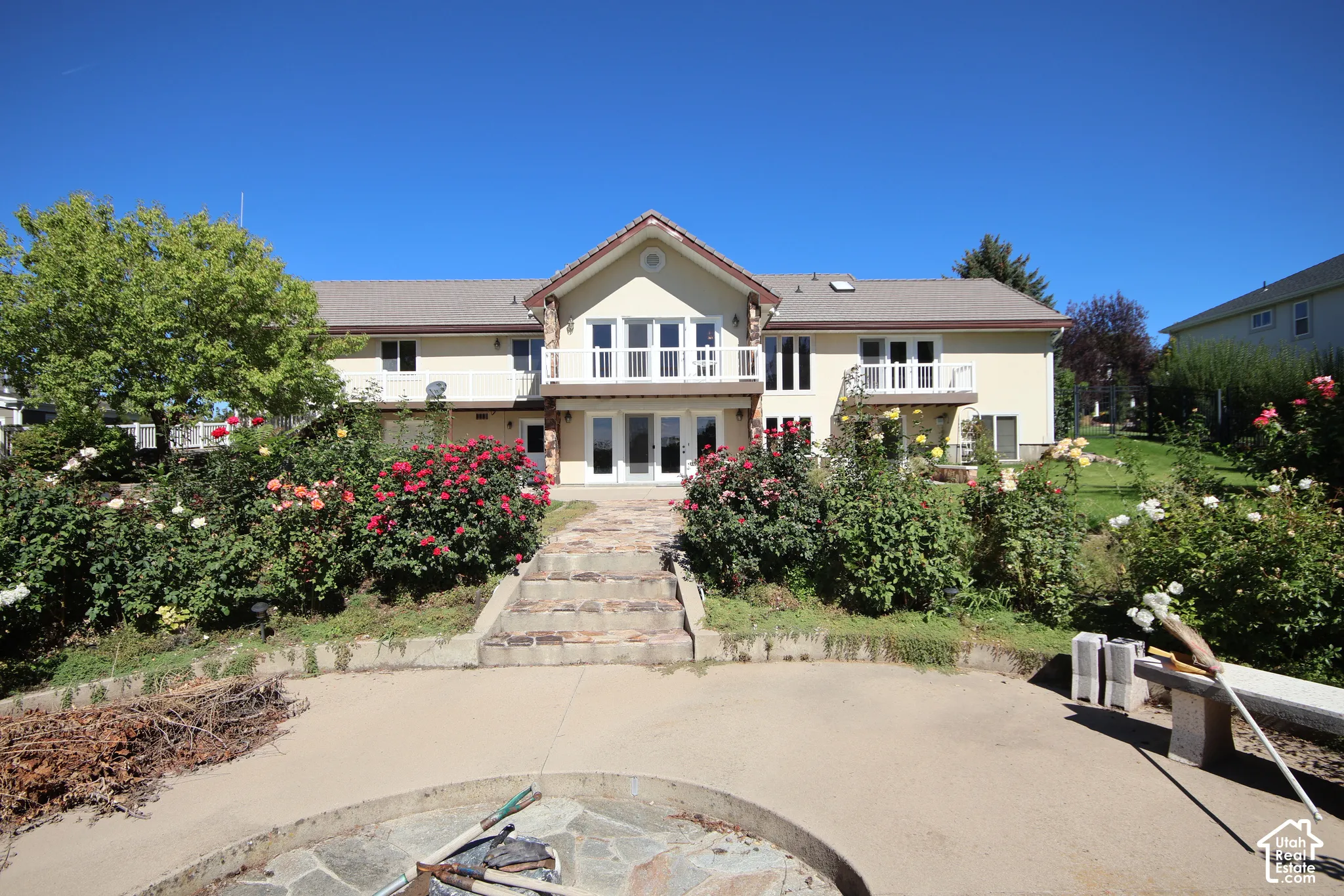 Multi-level dwelling with balconies, mature landscaping, and an exterior patio