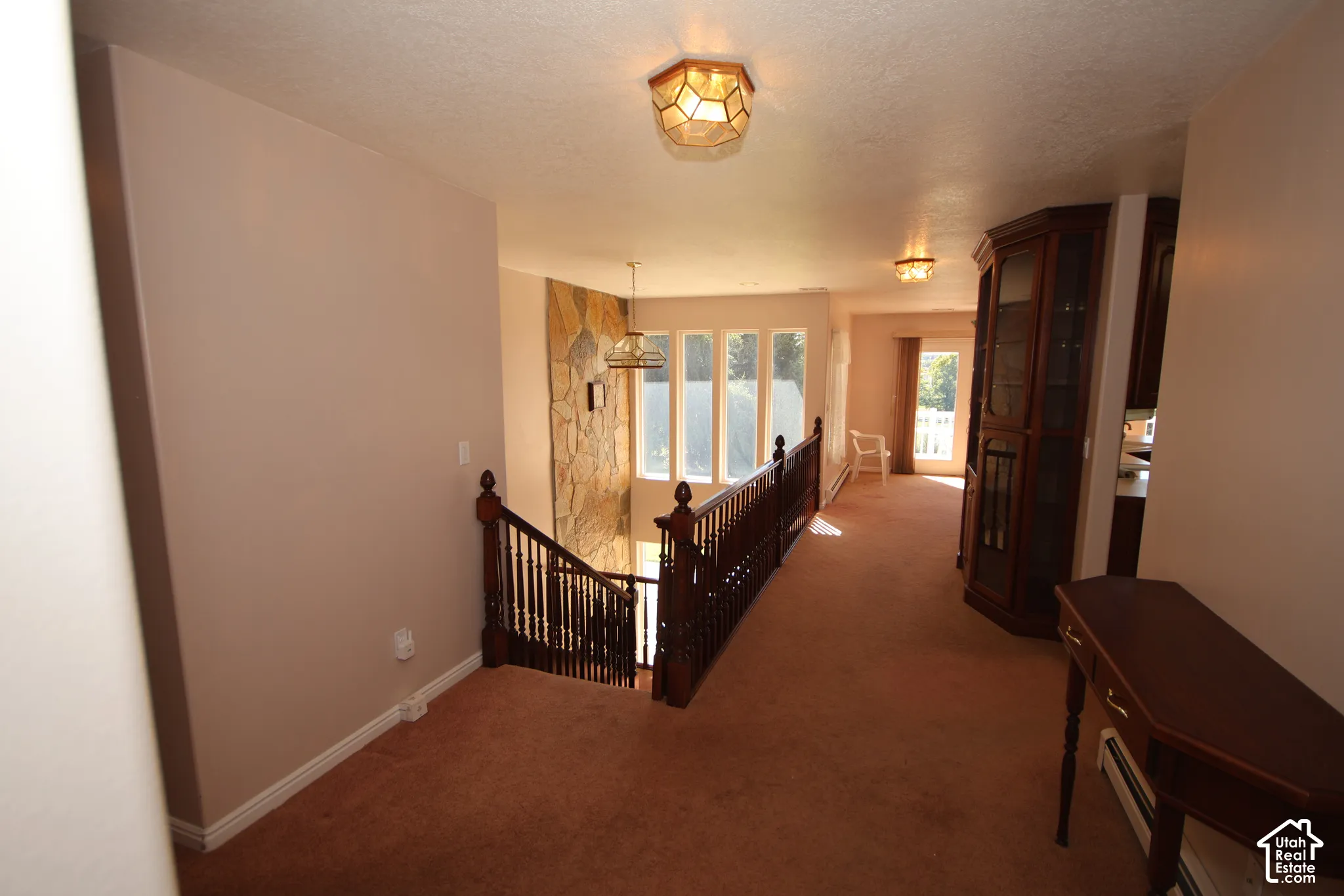 Staircase with wood banister and railing, stone accent wall, and multiple windows