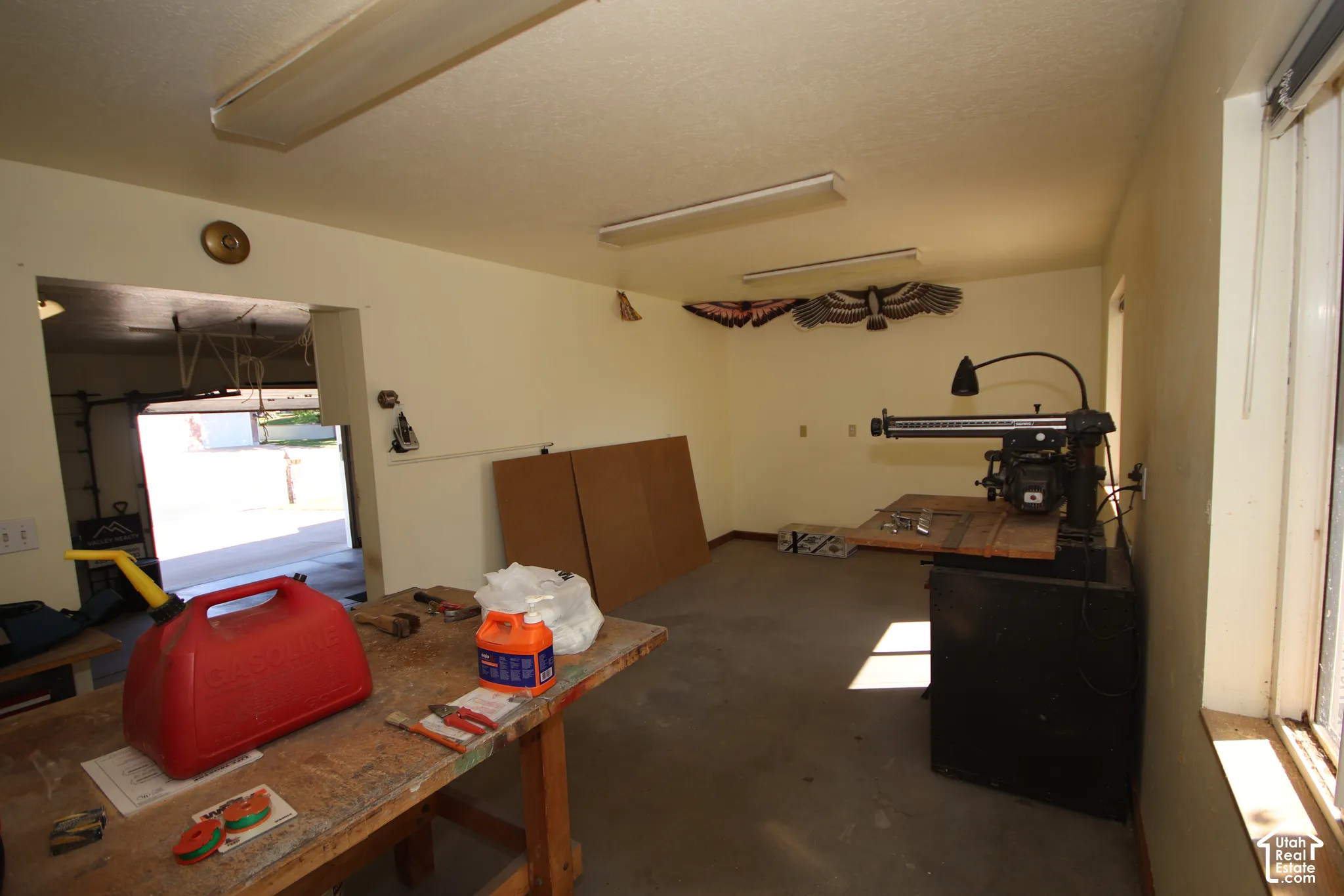 Workshop space with concrete flooring, fluorescent overhead lighting, and a window for natural illumination