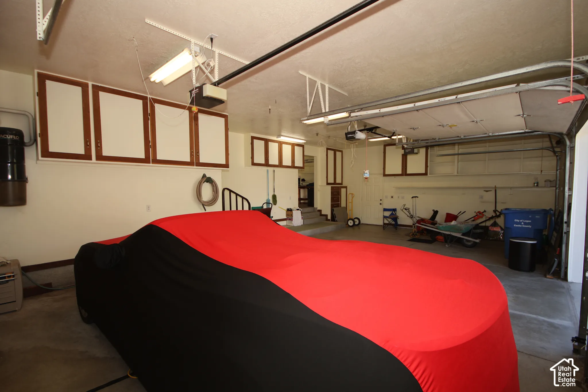 Garage with concrete flooring, overhead fluorescent lighting, and built-in wall cabinetry