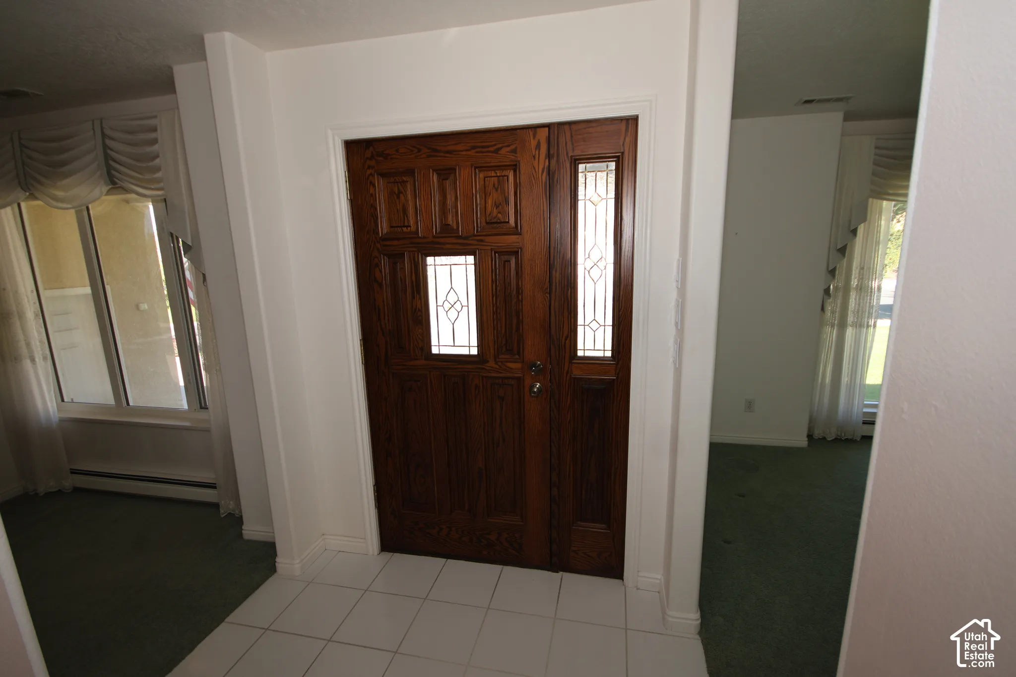 Wood-paneled entry door with decorative glass inserts, flanked by a coordinating sidelight