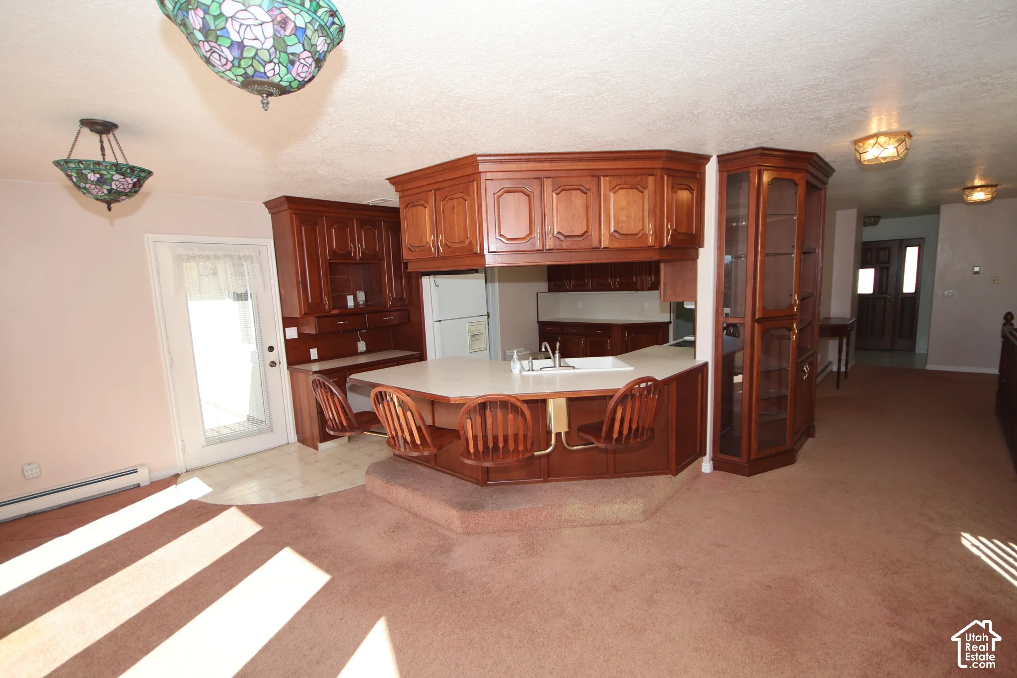 Kitchen with wood cabinetry, integrated breakfast bar, and corner display cabinet