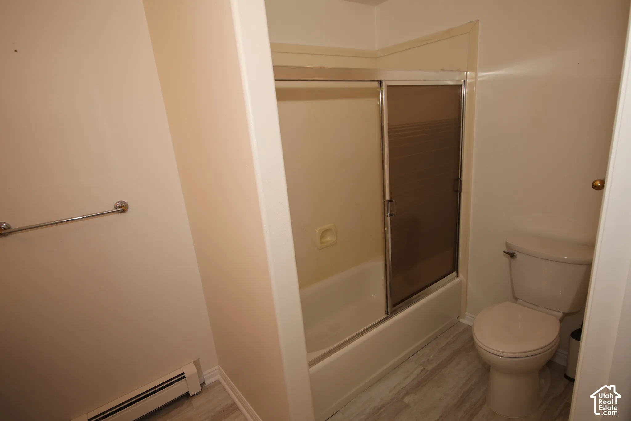 Tub and shower combination with sliding glass doors, toilet with tank, and wood-finish flooring