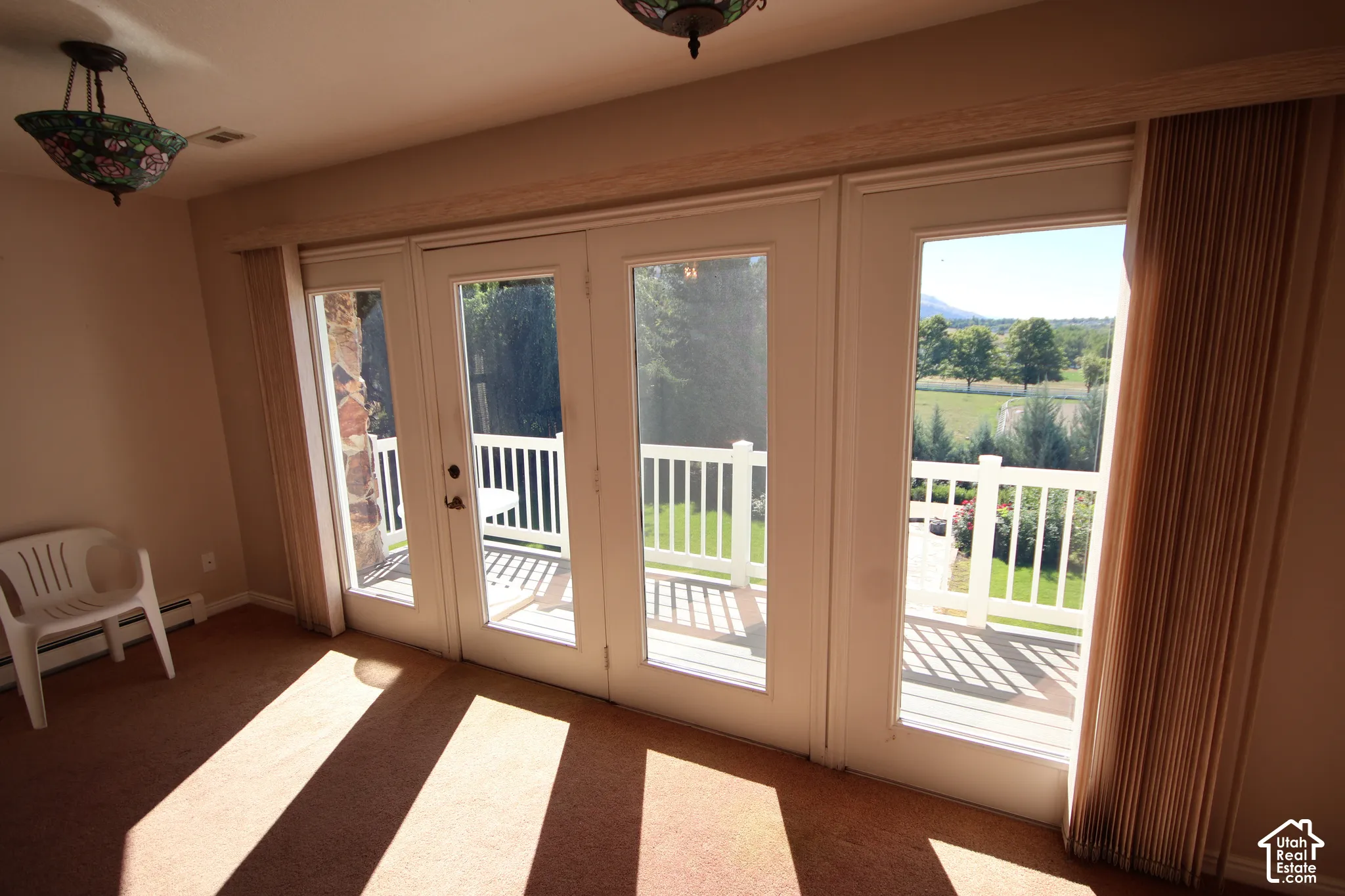 Triple French doors with full glass panels open to an outdoor deck featuring white balusters